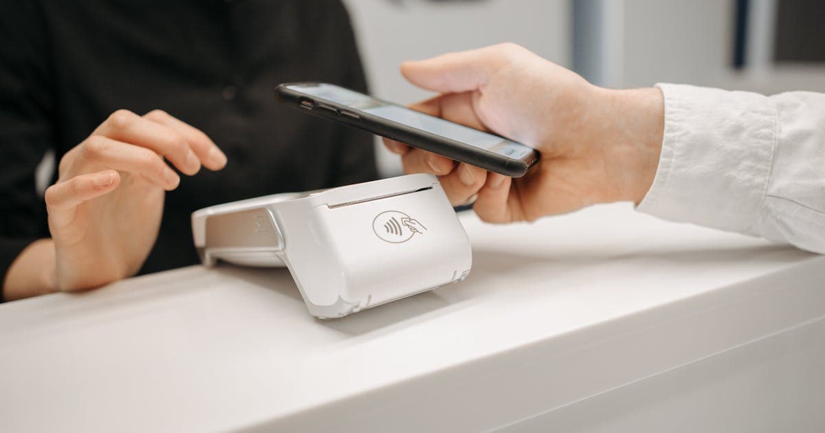 A person making a mobile payment using a smartphone, representing new deal comparison features